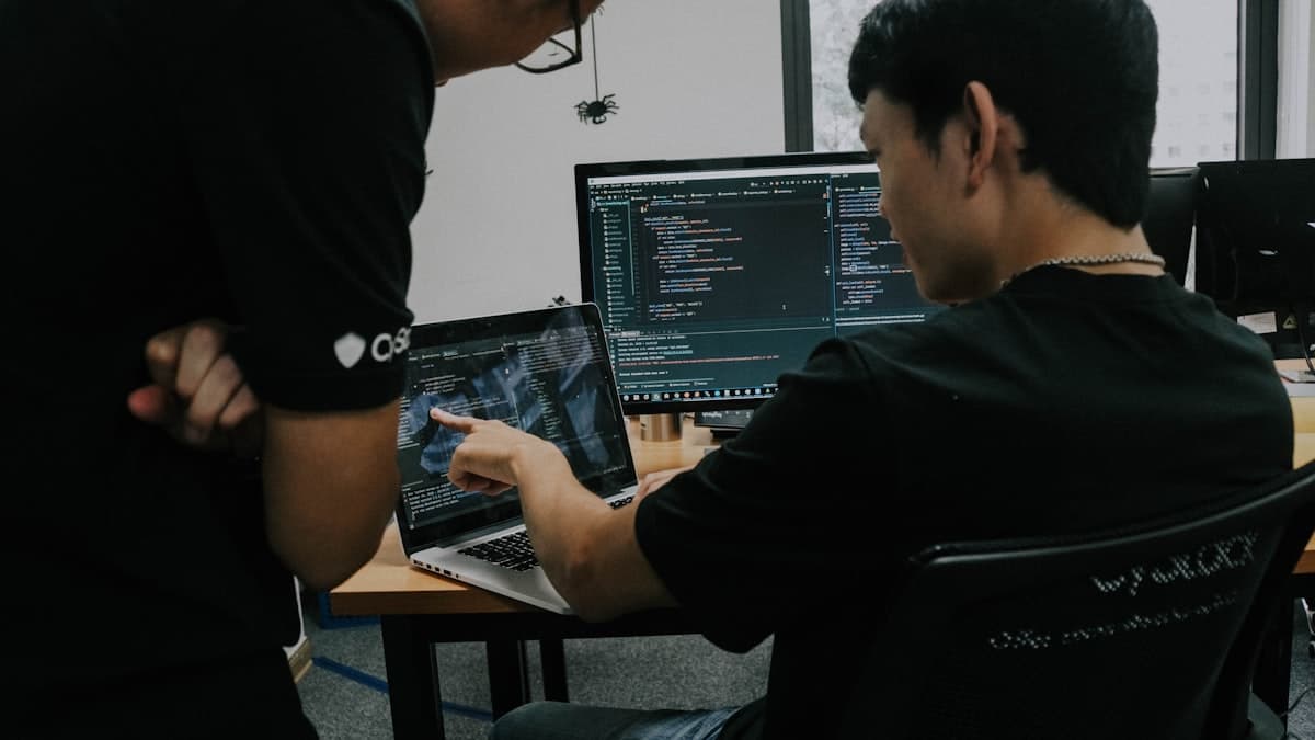 Dois profissionais de TI trabalhando em computadores em um escritório
