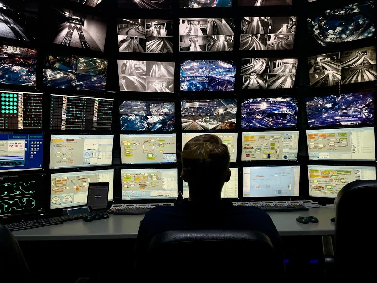 Profissional de segurança monitorando múltiplas telas de dados em uma central de operações