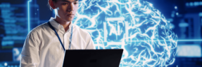 Homem mexendo no computador com imagem de cérebro no fundo com sigla "AI", que significa o universo da inteligência artificial, deep learning e machine learning.